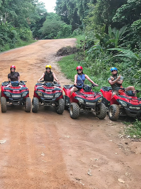 Tourists on ATVs in Phuket, riding through lush forest trails.
