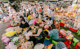 Bustling market scene with vendors and visitors enjoying local breakfast dishes in Da Nang.
