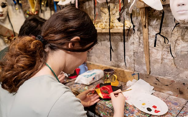 Person painting a Venetian mask in a workshop, Venice.