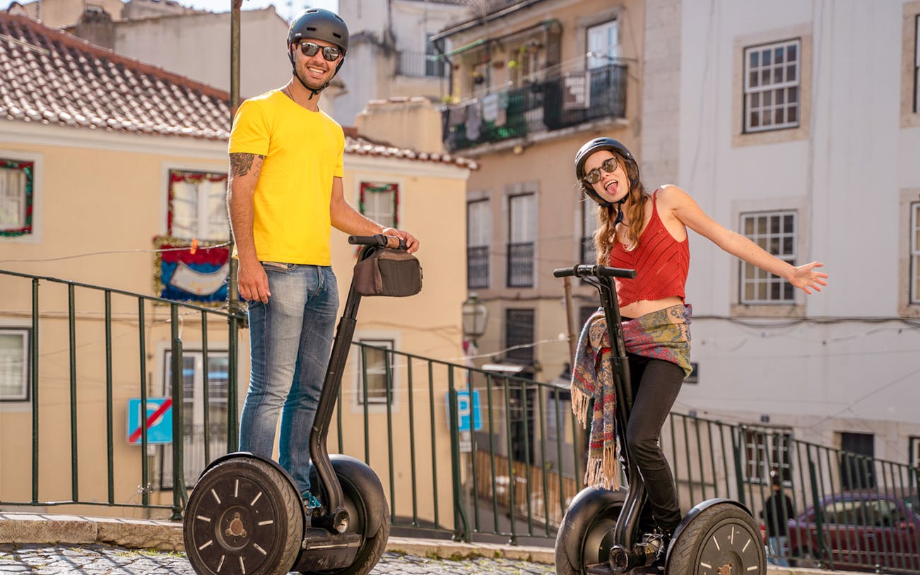 Tourists on Segways exploring Alfama's medieval streets in Lisbon.