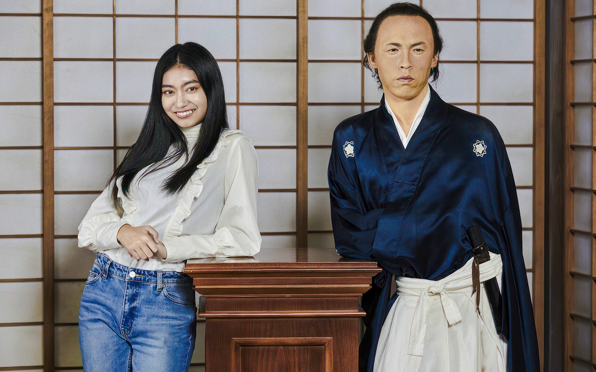 Person posing with a wax figure in traditional attire at Madame Tussauds Tokyo.