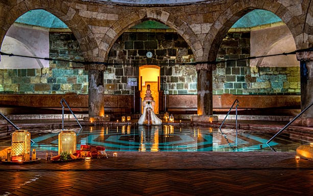 Rudas Bath interior with pool and candles, New Year's Eve party setup in Budapest.