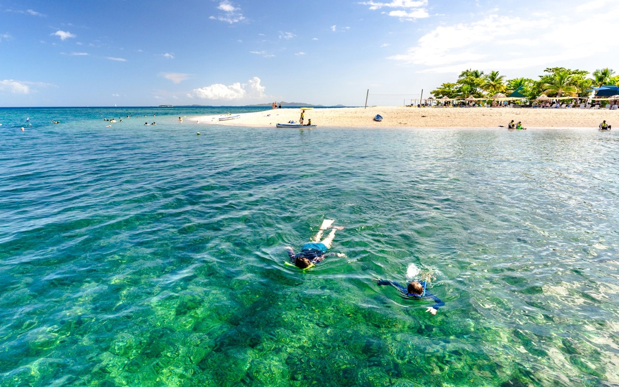 Snorkelers exploring clear waters near South Sea Island, Fiji.