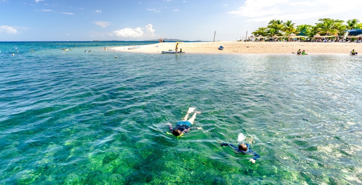 Snorkelers exploring clear waters near South Sea Island, Fiji.