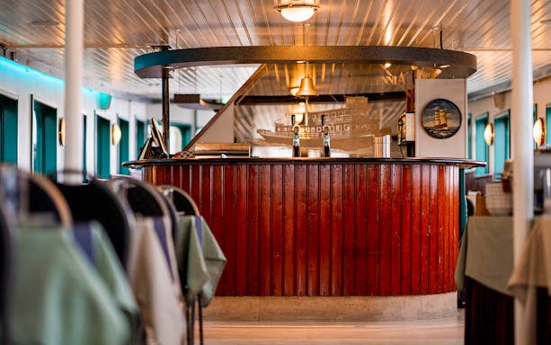 Bar area inside Rotterdam Historical Cruise with wooden paneling and nautical decor.