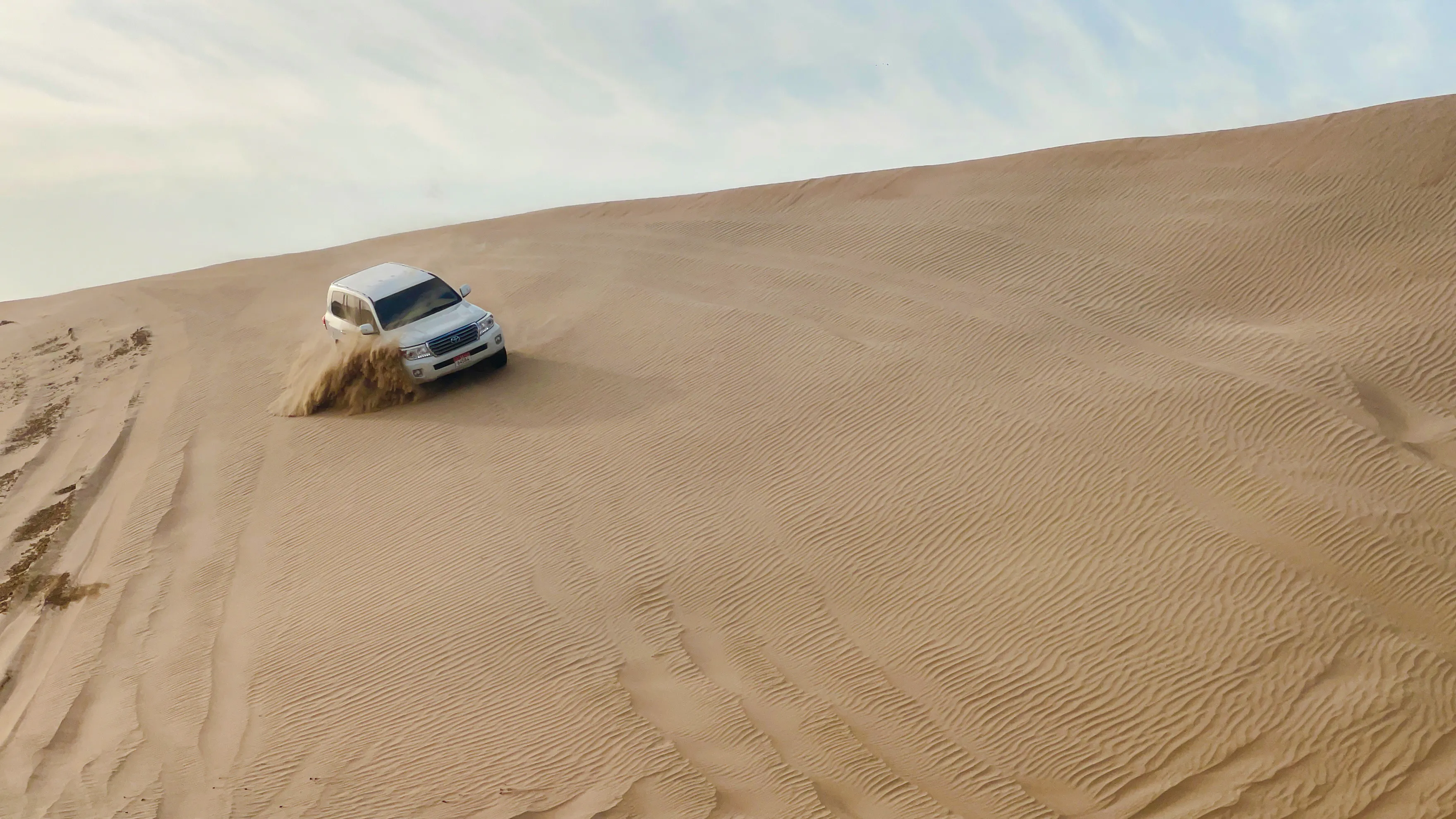SUV driving on sand dunes during Abu Dhabi sunrise desert safari.