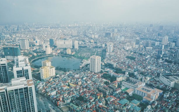 Aerial view of Hanoi cityscape from Lotte Observation Deck, featuring high-rise buildings and a central lake.