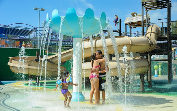 Visitors enjoying water play area at Illa Fantasia Water Park with slides and fountains.
