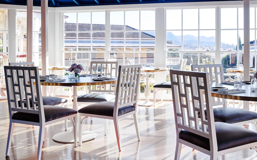 Dining area with set tables and chairs overlooking Hunter Valley vineyards.