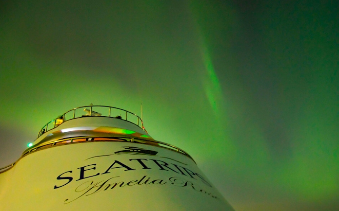 Northern lights over yacht deck on Northern Lights Yacht Cruise.