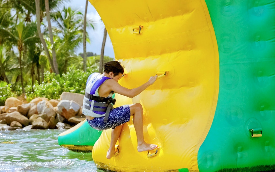 Person climbing inflatable obstacle at HydroDash Singapore water park.