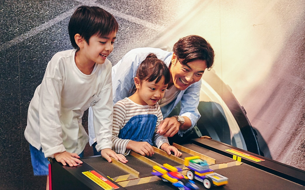 Children and adult playing with LEGO cars at LEGOLAND Discovery Center Tokyo.