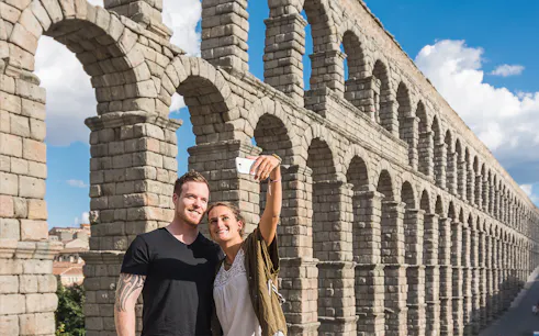 Visitors taking a selfie at the Roman Aqueduct in Segovia.
