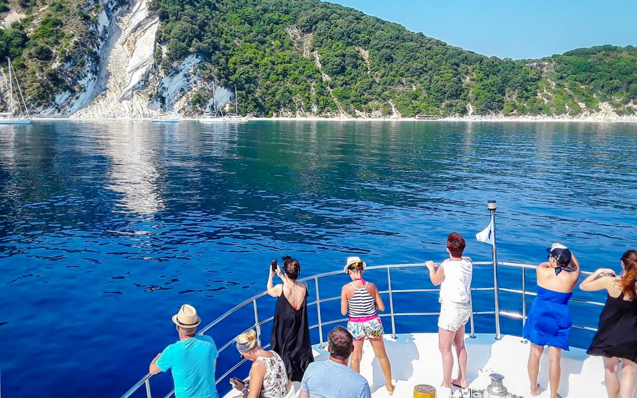 People enjoying a cruise near Ithaca, Greece, with scenic coastal views.