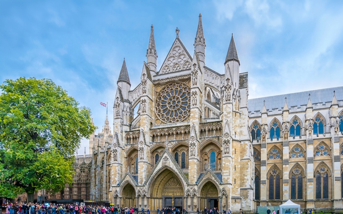 Westminster Abbey facade with visitors, London.