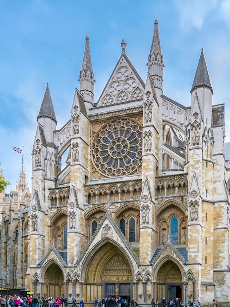 Westminster Abbey facade with visitors, London.