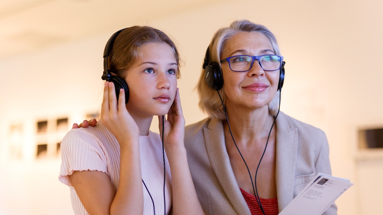 A young girl and a woman engaging with an audio guide