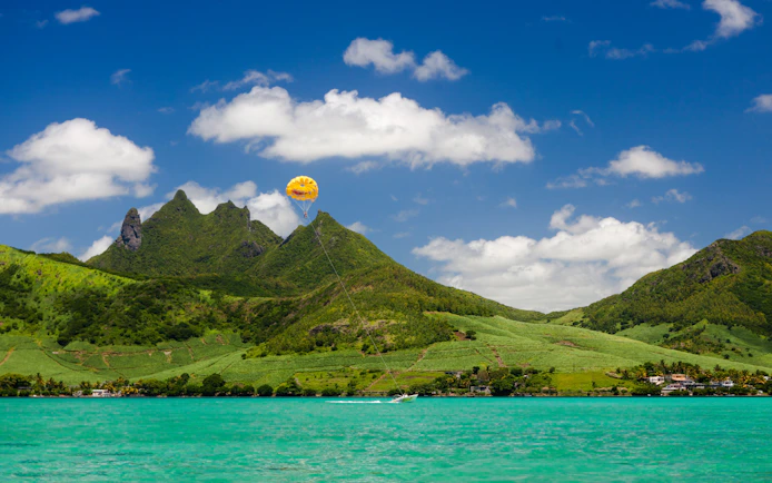 Parasailing over lush mountains and turquoise waters on the east coast of Mauritius.