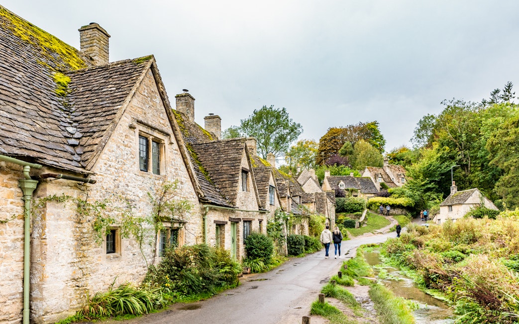 Cotswolds village path with stone cottages and greenery, part of London to Broadway Tower tour.