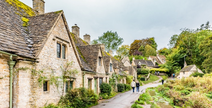 Cotswolds village path with stone cottages and greenery, part of London to Broadway Tower tour.