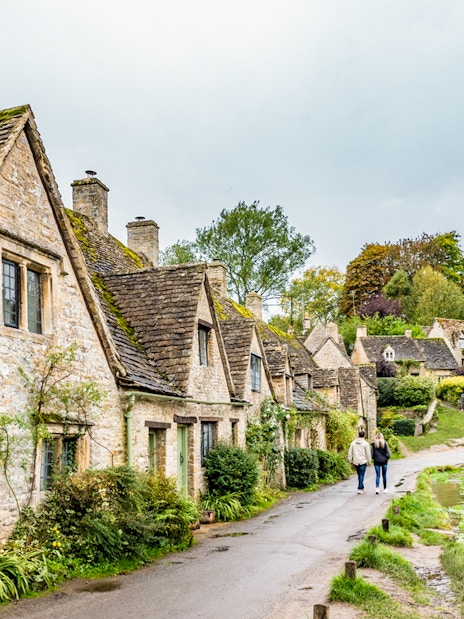 Cotswolds village path with stone cottages and greenery, part of London to Broadway Tower tour.