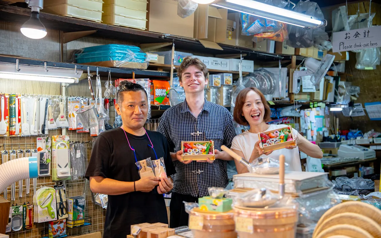 Tour participants holding sushi bento boxes at Tsukiji Market during a sushi making and tuna tasting experience.