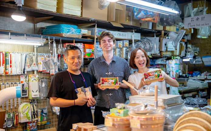 Tour participants holding sushi bento boxes at Tsukiji Market during a sushi making and tuna tasting experience.