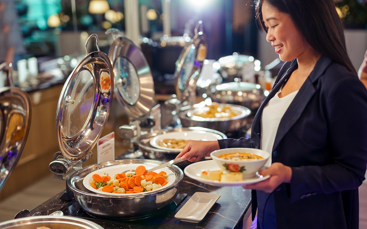 Buffet selection at SATS Plaza Premium Lounge, Singapore, with a guest serving food.