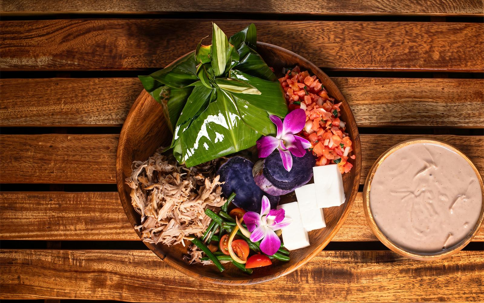 Traditional Hawaiian feast with taro, pork, and tropical flowers at Old Lahaina Luau.
