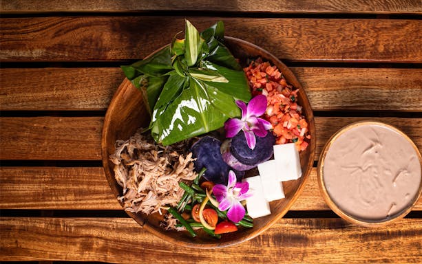 Traditional Hawaiian feast with taro, pork, and tropical flowers at Old Lahaina Luau.