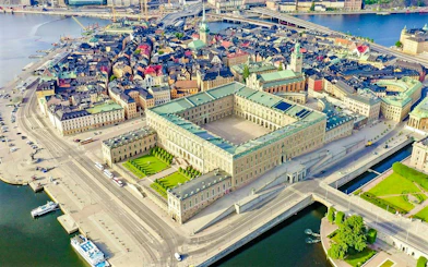 Aerial view of the Royal Palace in Stockholm surrounded by cityscape and waterways.