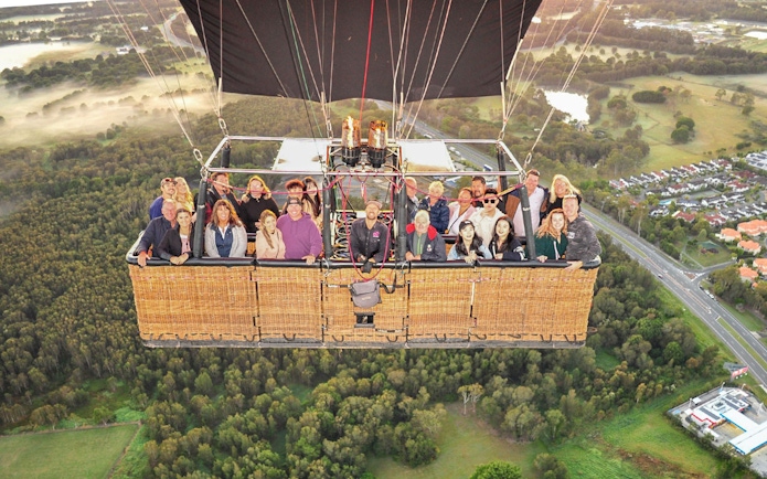 Group enjoying a hot air balloon flight over scenic landscape with optional transfers.