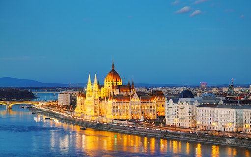 Parliament building in Budapest illuminated at night along the Danube River.