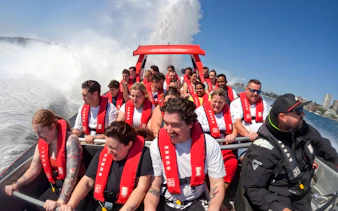 People enjoying a thrilling OZ Jet Boating ride in Sydney, with water splashing around.
