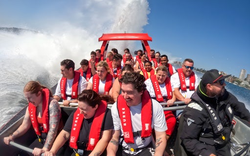 People enjoying a thrilling OZ Jet Boating ride in Sydney, with water splashing around.
