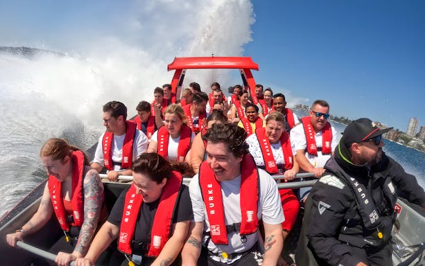People enjoying a thrilling OZ Jet Boating ride in Sydney, with water splashing around.