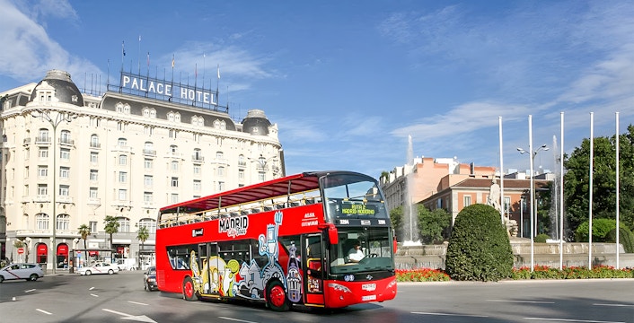 Hop-On Hop-Off bus near Royal Palace in Madrid cityscape.