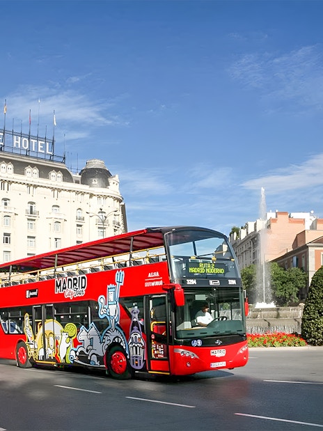 Hop-On Hop-Off bus near Royal Palace in Madrid cityscape.