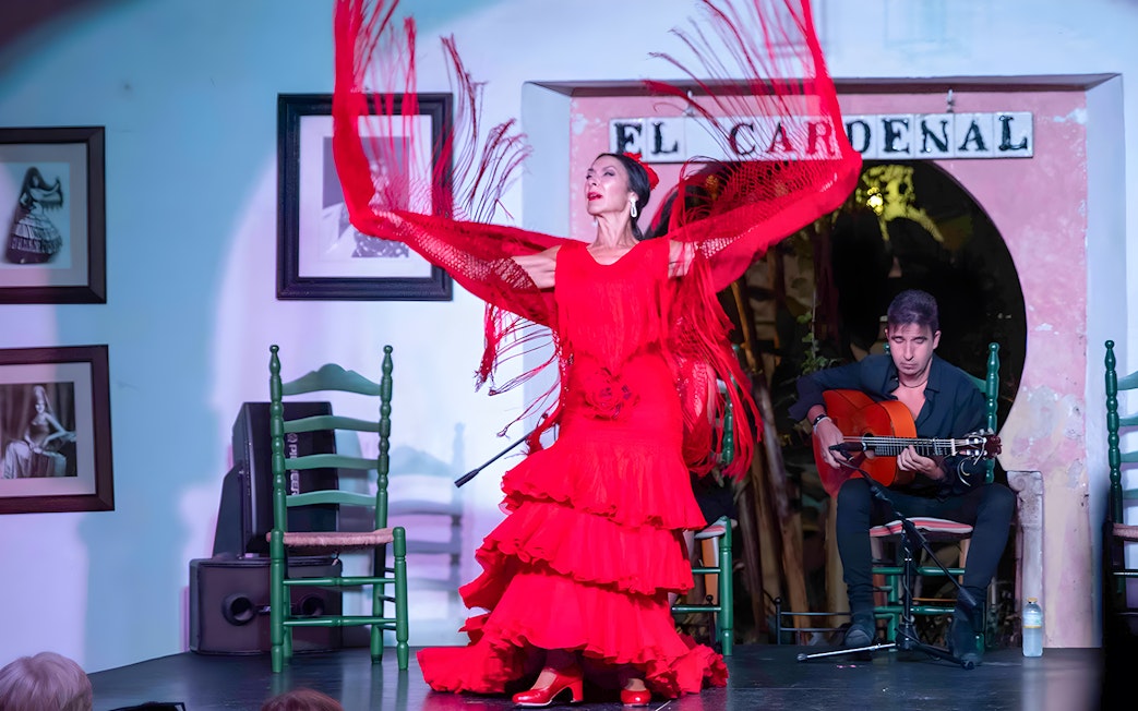 Flamenco dancer performing at Tablao Cardenal with guitarist in the background.