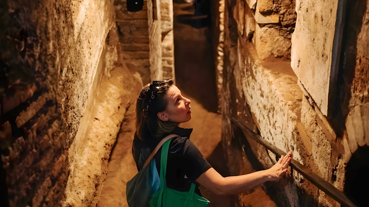 tourist walking through the ancient Roman Catacombs during the Capuchin Crypts & Basilica of San Nicola Guided Tour in Rome