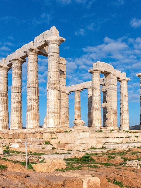 Temple of Poseidon ruins at Sounion, Attica, Greece under a blue sky.