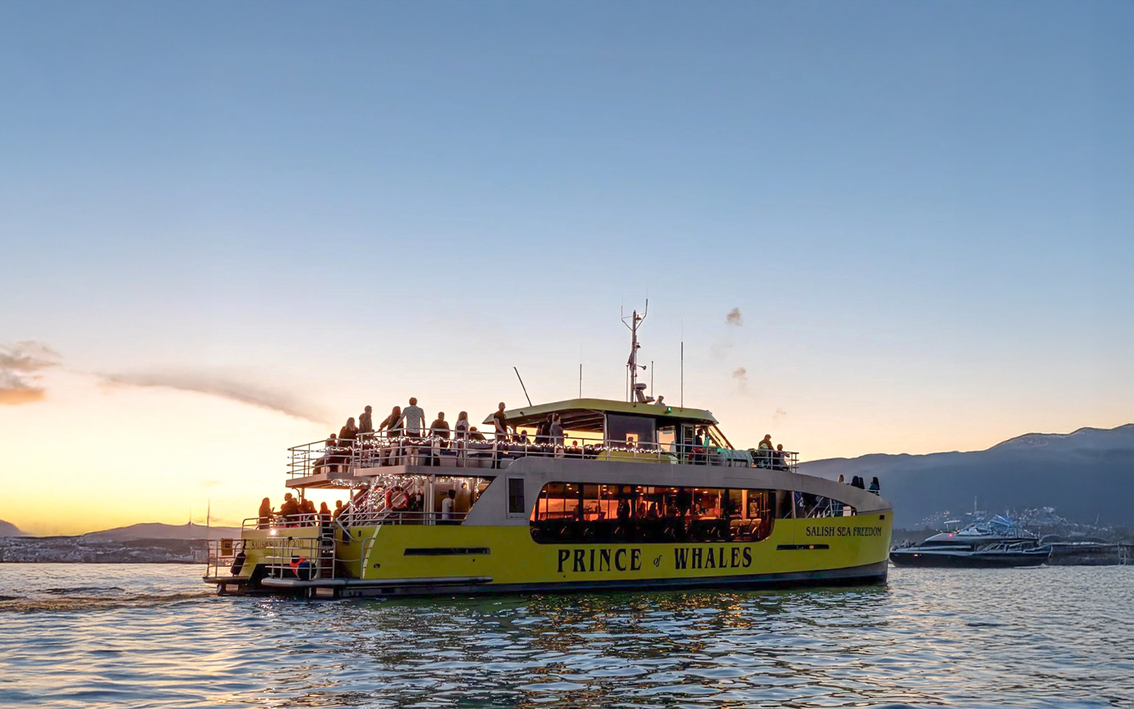 Whale watching boat "Prince of Whales" on the water at sunset with passengers on deck.