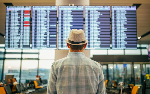 Traveler viewing flight information screens at Newark Liberty International Airport.