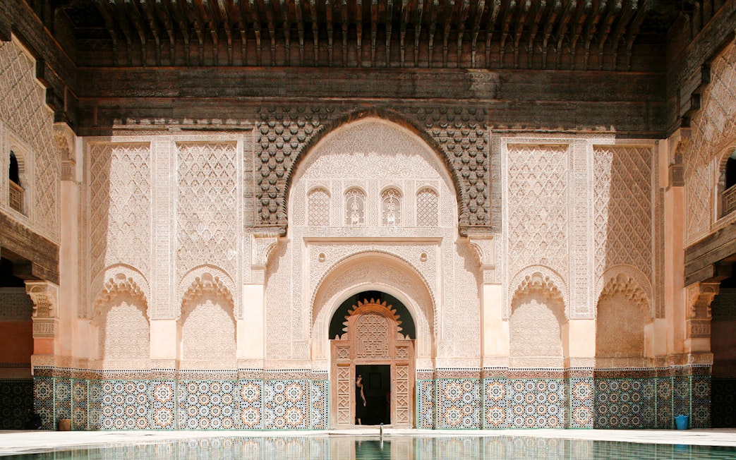 Ben Youssef Madrasa courtyard with intricate carvings and mosaic tiles in Marrakesh, Morocco.