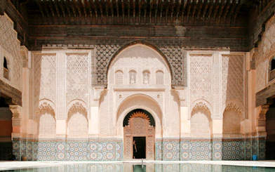 Ben Youssef Madrasa courtyard with intricate carvings and mosaic tiles in Marrakesh, Morocco.