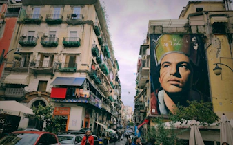 Street in Naples with large mural, part of Curse of Naples Mafia Secrets self-guided city exploration game.