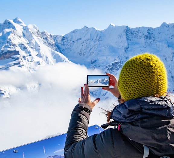 Person photographing snowy Swiss Alps on Zurich to Jungfraujoch tour.