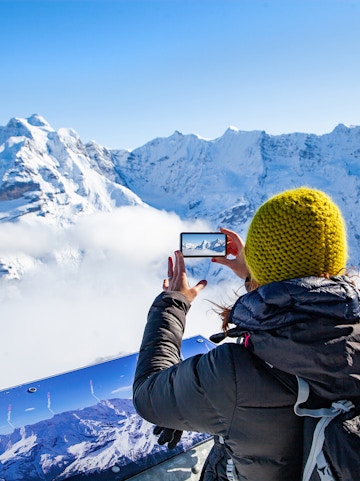 Person photographing snowy Swiss Alps on Zurich to Jungfraujoch tour.