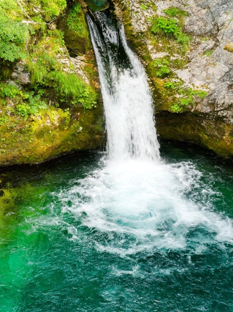 Waterfall flowing into the vibrant blue waters of the Blue Eye spring in Albania.