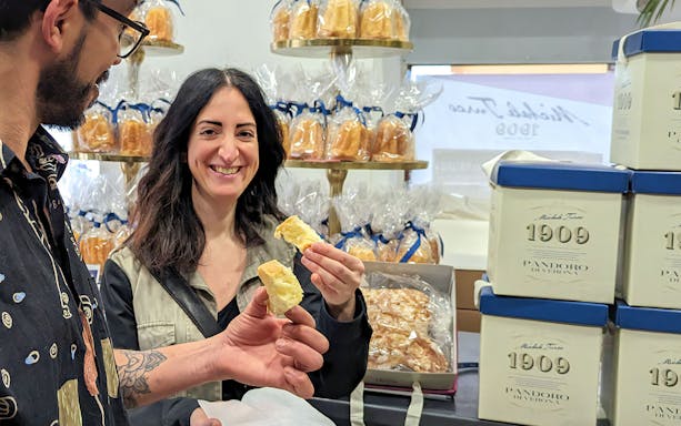 Tourists sampling pandoro at a bakery in Verona during a guided food tour.